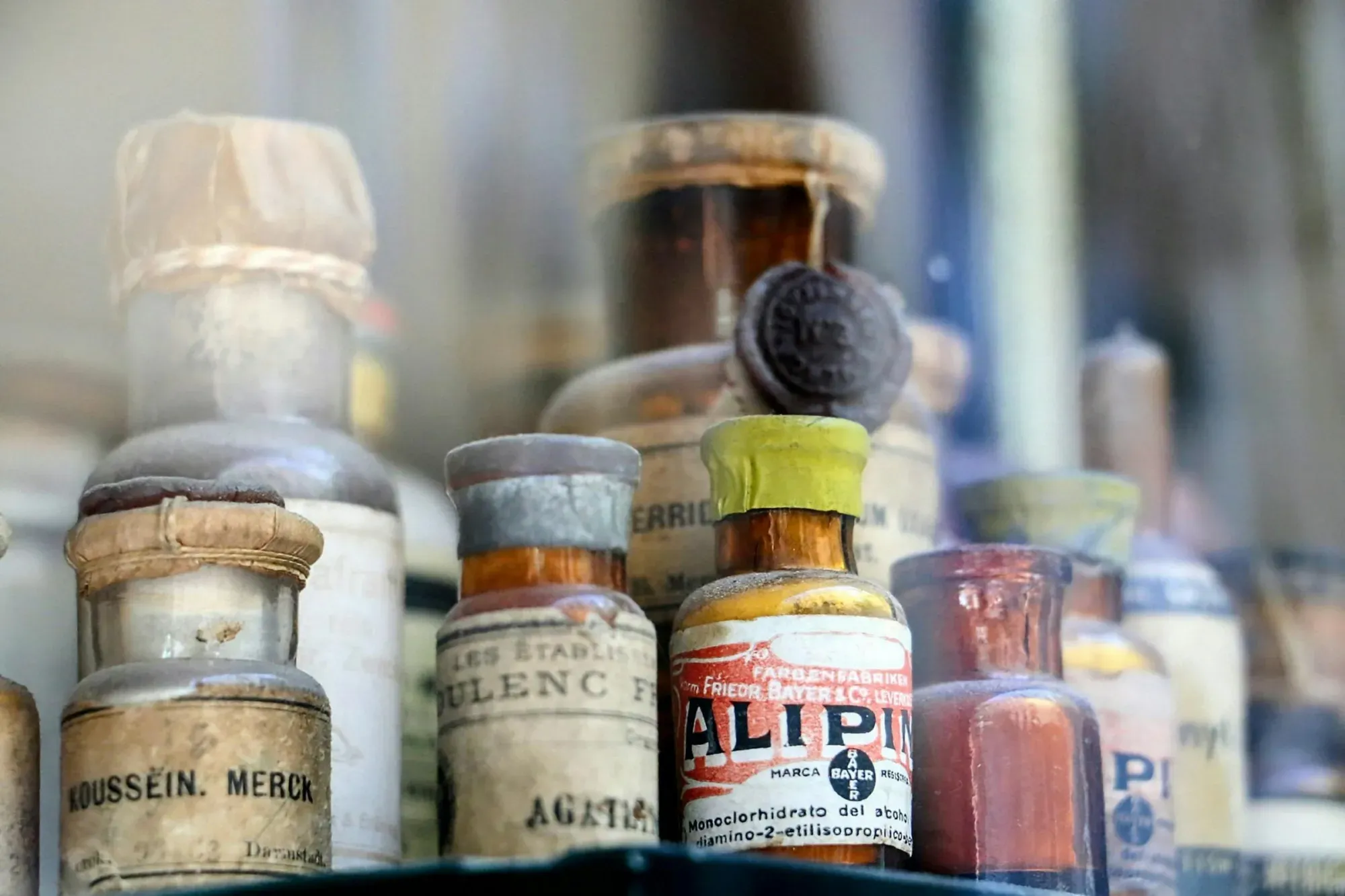 Una colección de frascos farmacéuticos antiguos expuestos en una vitrina de cristal antigua.