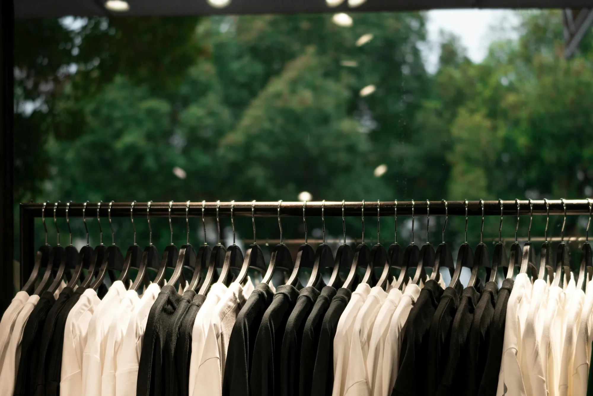 Una exhibición de ropa moderna con camisas blancas y negras en perchas dentro de una tienda de moda.