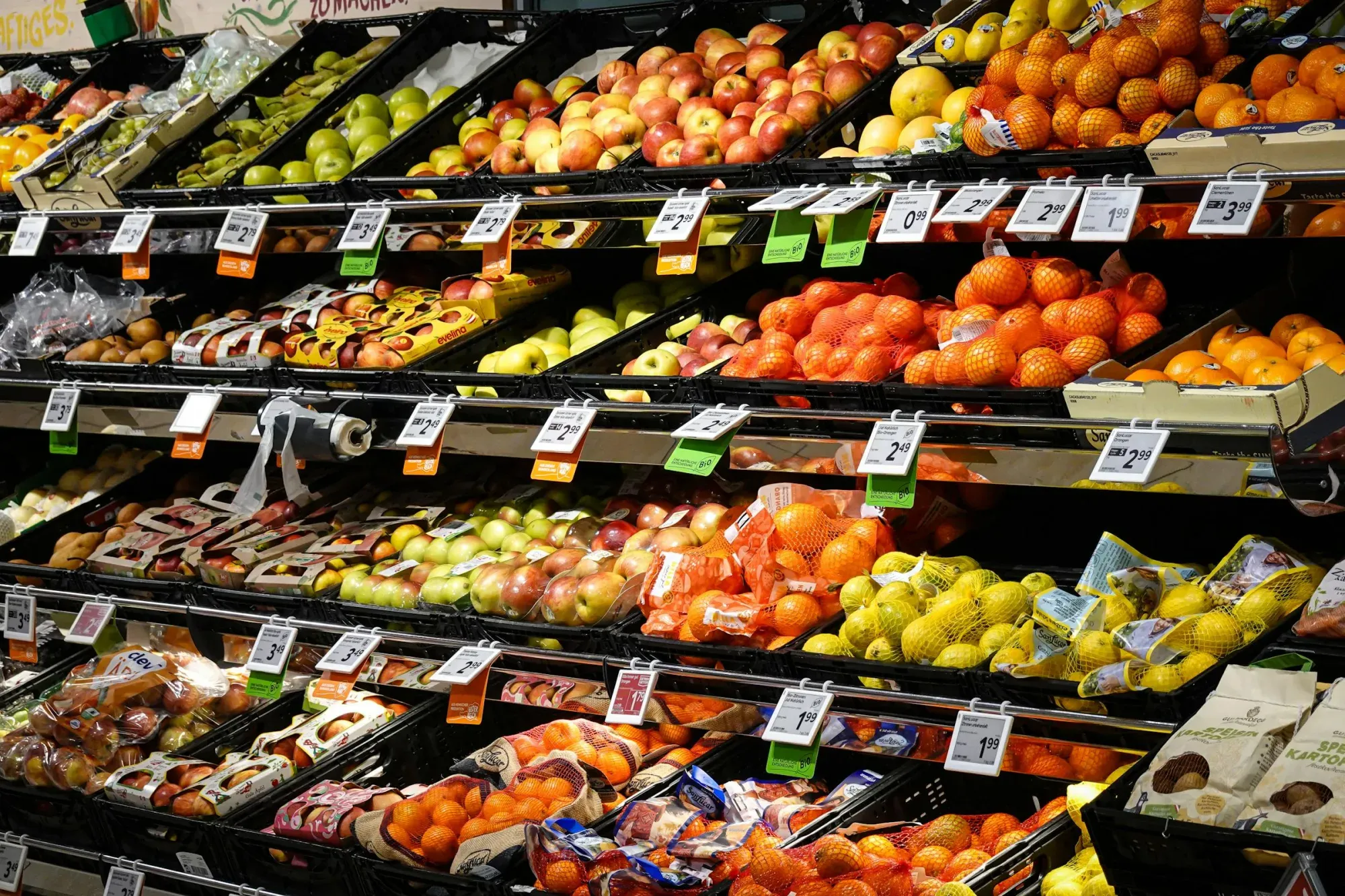 Surtido colorido de frutas frescas cuidadosamente dispuestas en los estantes del supermercado, ideal para temas de alimentación saludable.