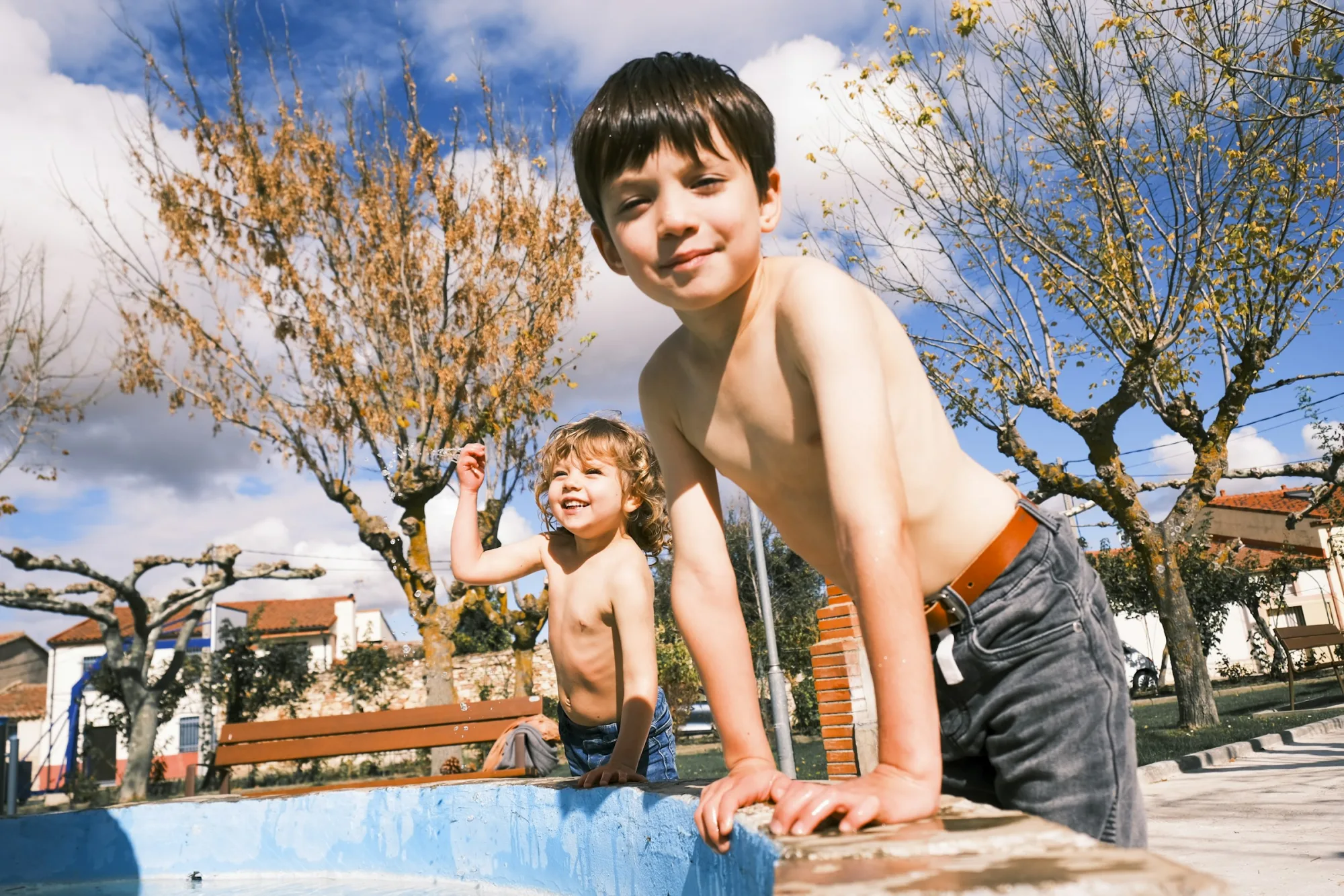 Two shirtless boys by a pool