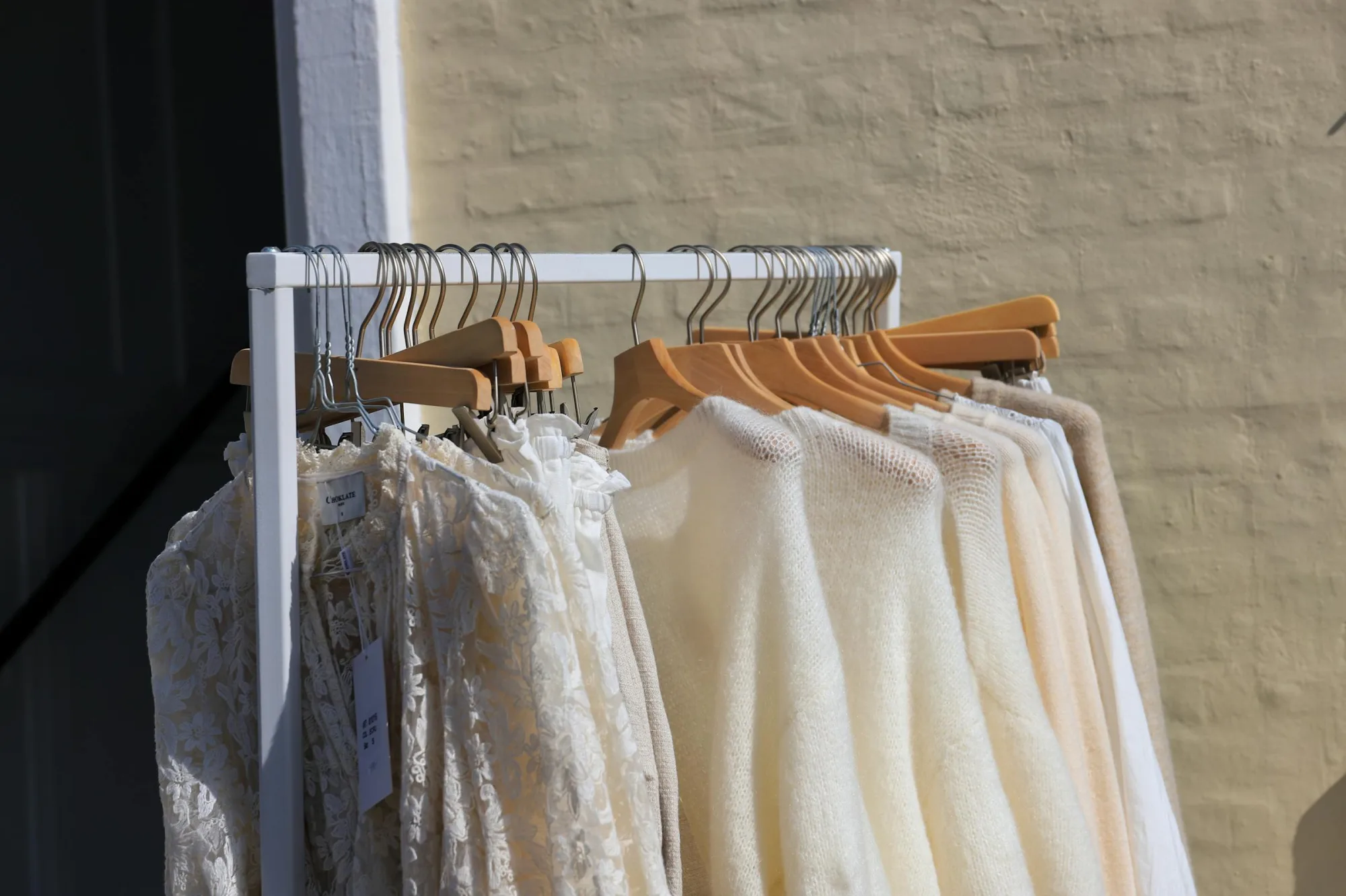 Una colección de elegantes suéteres y vestidos en un estante en Løkken, la tienda de ropa para actividades al aire libre de Dinamarca.
