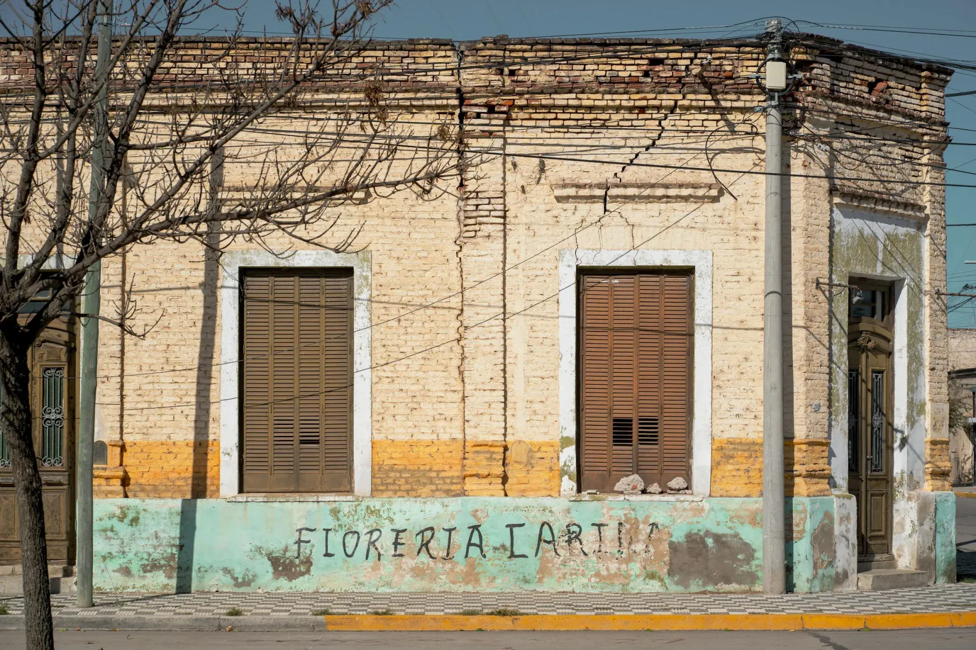 Encantadora fachada de ladrillo de una antigua florería en Oliva, Córdoba, Argentina, con pintura turquesa vibrante.