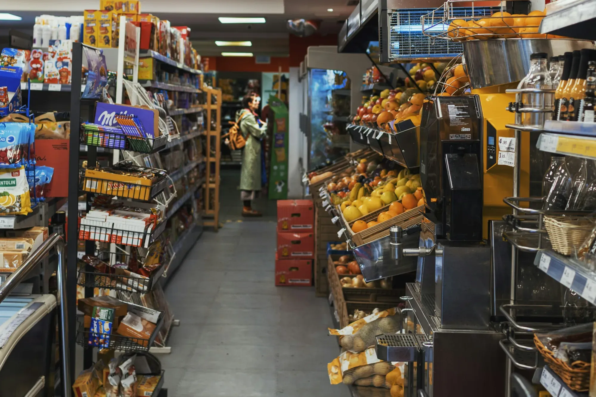 A person shops in a well-stocked grocery store aisle.